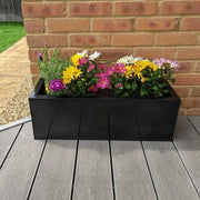 A lineup of long planters, creating a natural border along the patio.